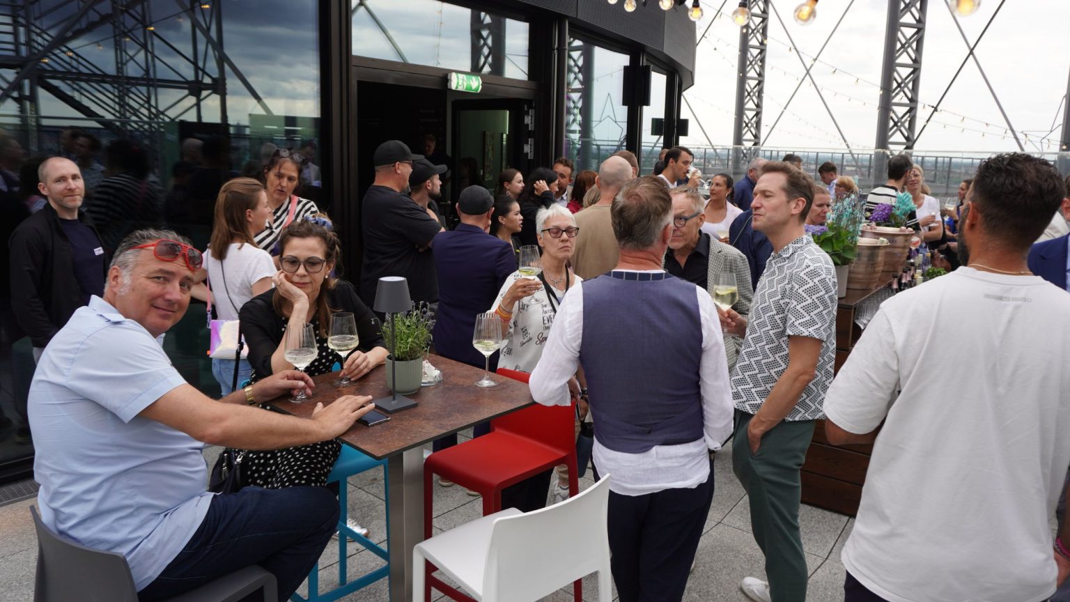Gäste stehen und sitzen auf der Terrasse des Gasometers und unterhalten sich angeregt