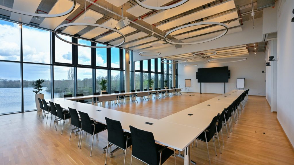 Meetingraum Eventlocation EUREF-Campus Düsseldorf mit Reihen-Bestuhlung und Fensterfront mit Seeblick