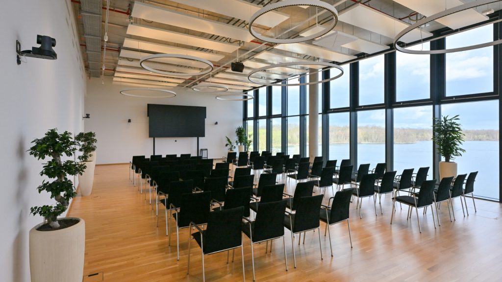 Meetingraum Eventlocation EUREF-Campus Düsseldorf mit Reihen-Bestuhlung und Fensterfront mit Seeblick