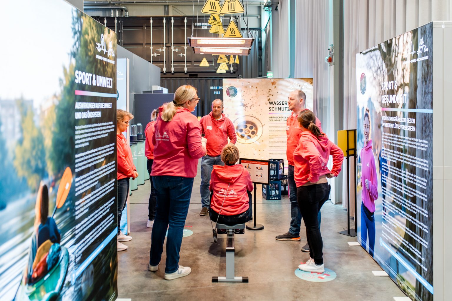 Aussteller in der W26, Mitarbeitende der Firma mit roten Kapuzenpullovern