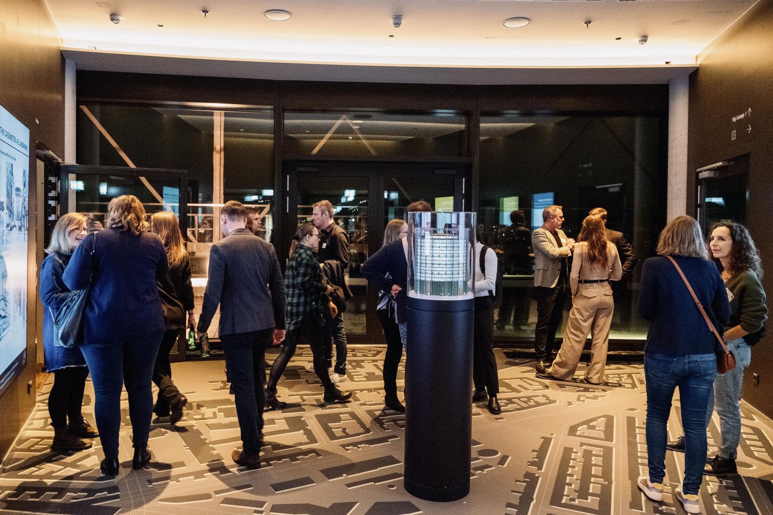 Gäste in der Gasometer Sky Bar bei Gesprächen. In der Mitte steht ein Modell des Gasometers.