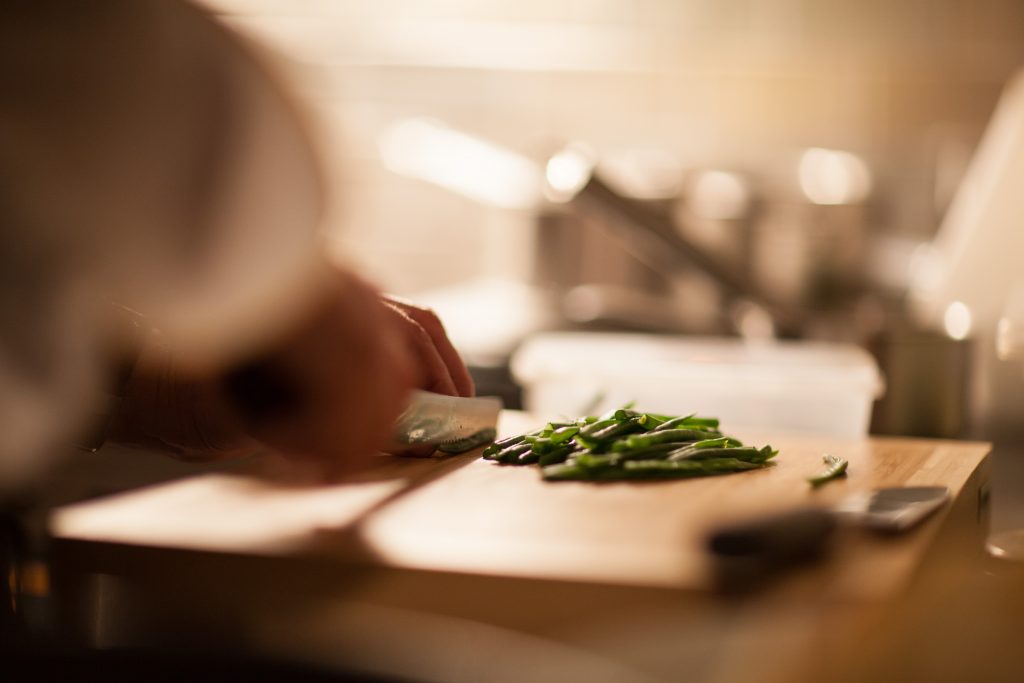Zwei Hände schneiden Gemüse