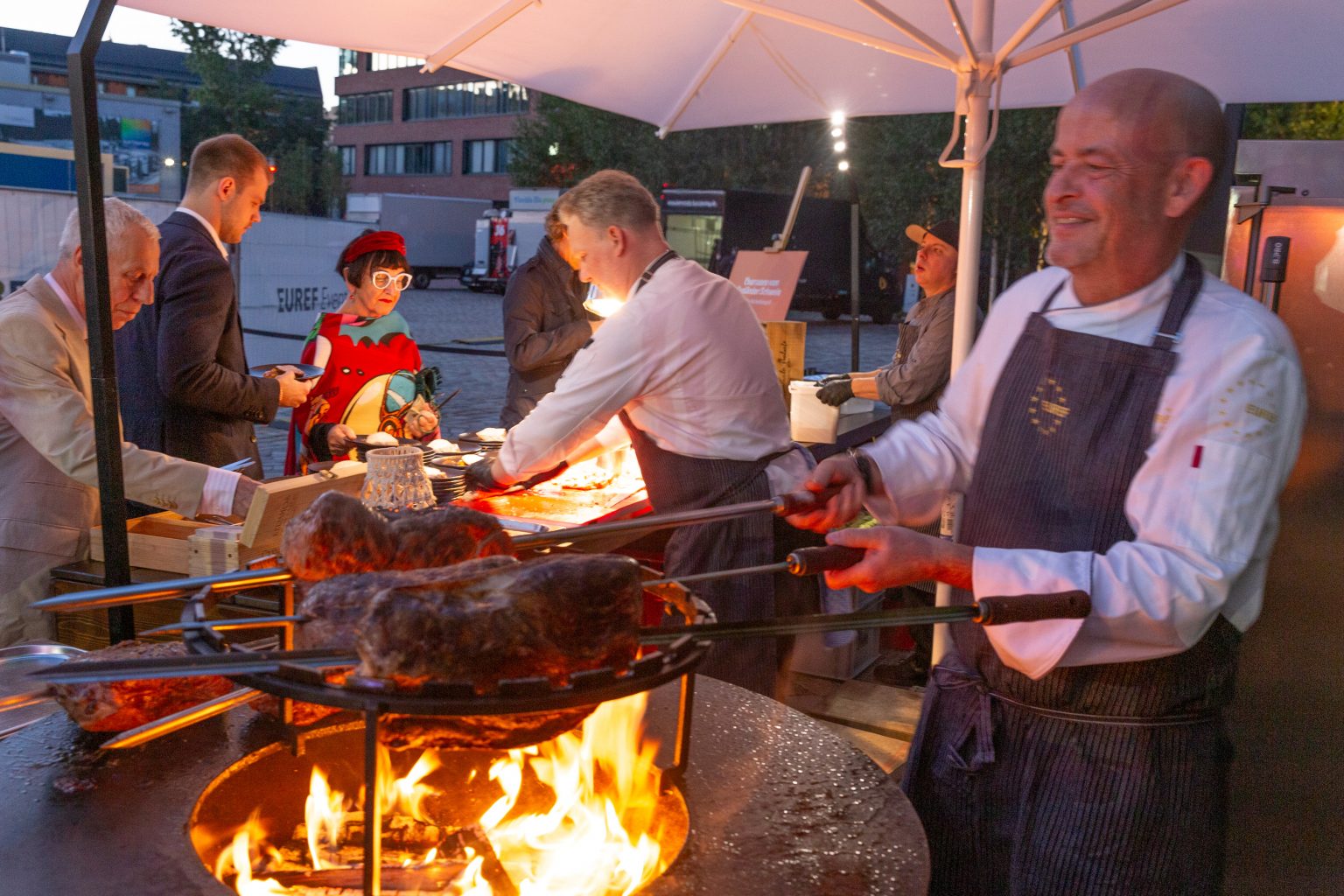 Thomas Kammeier steht an einer Live Cooking Station und grillt Fleisch über offenem Feuer