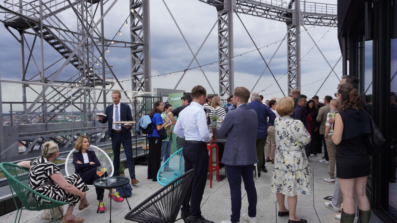Gäste stehen und sitzen auf der Terrasse des Gasometers und unterhalten sich angeregt
