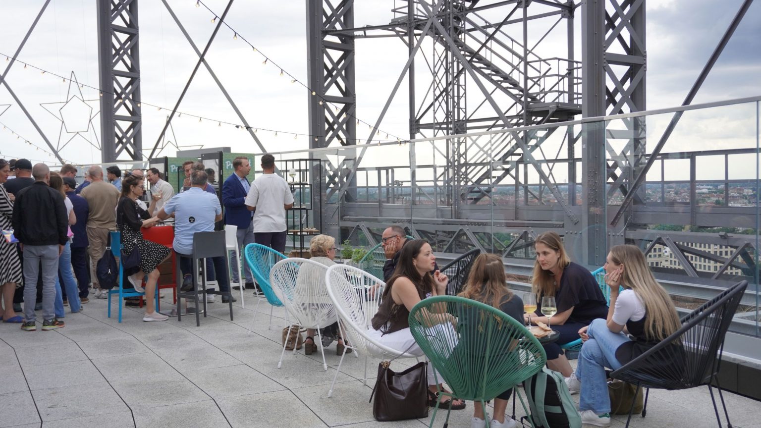 Gäste stehen und sitzen auf der Terrasse des Gasometers und unterhalten sich angeregt