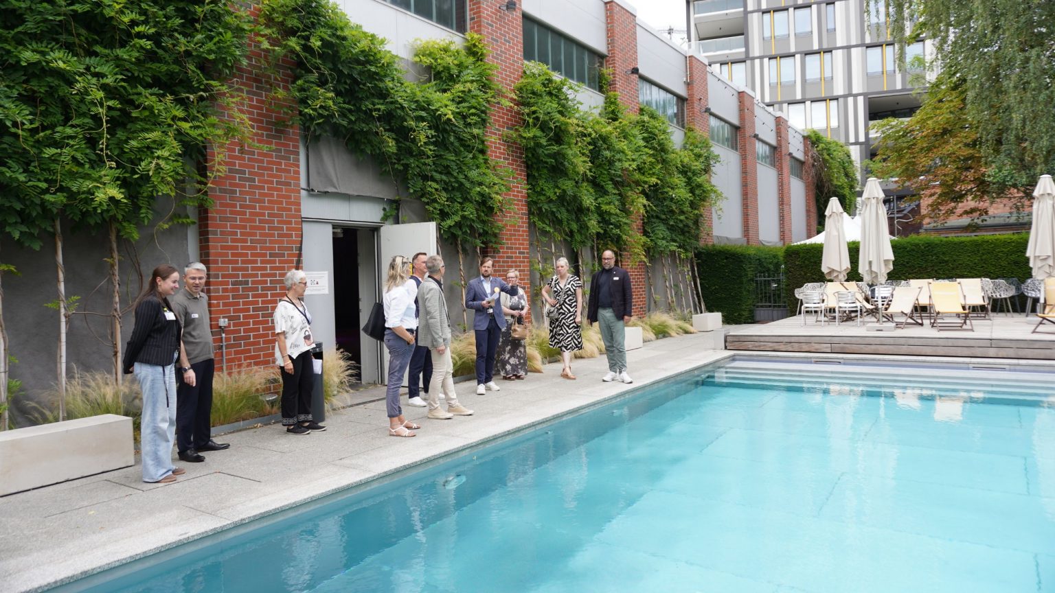 Eine Gruppe von Menschen steht bei einer Führung am Pool auf dem EUREF-Campus Berlin
