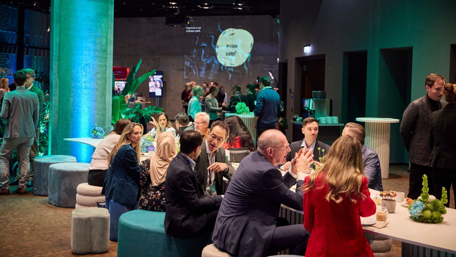 Gäste bei der Veranstaltung im grün und blau dekorierten und beleuchteten Veranstaltungsraum