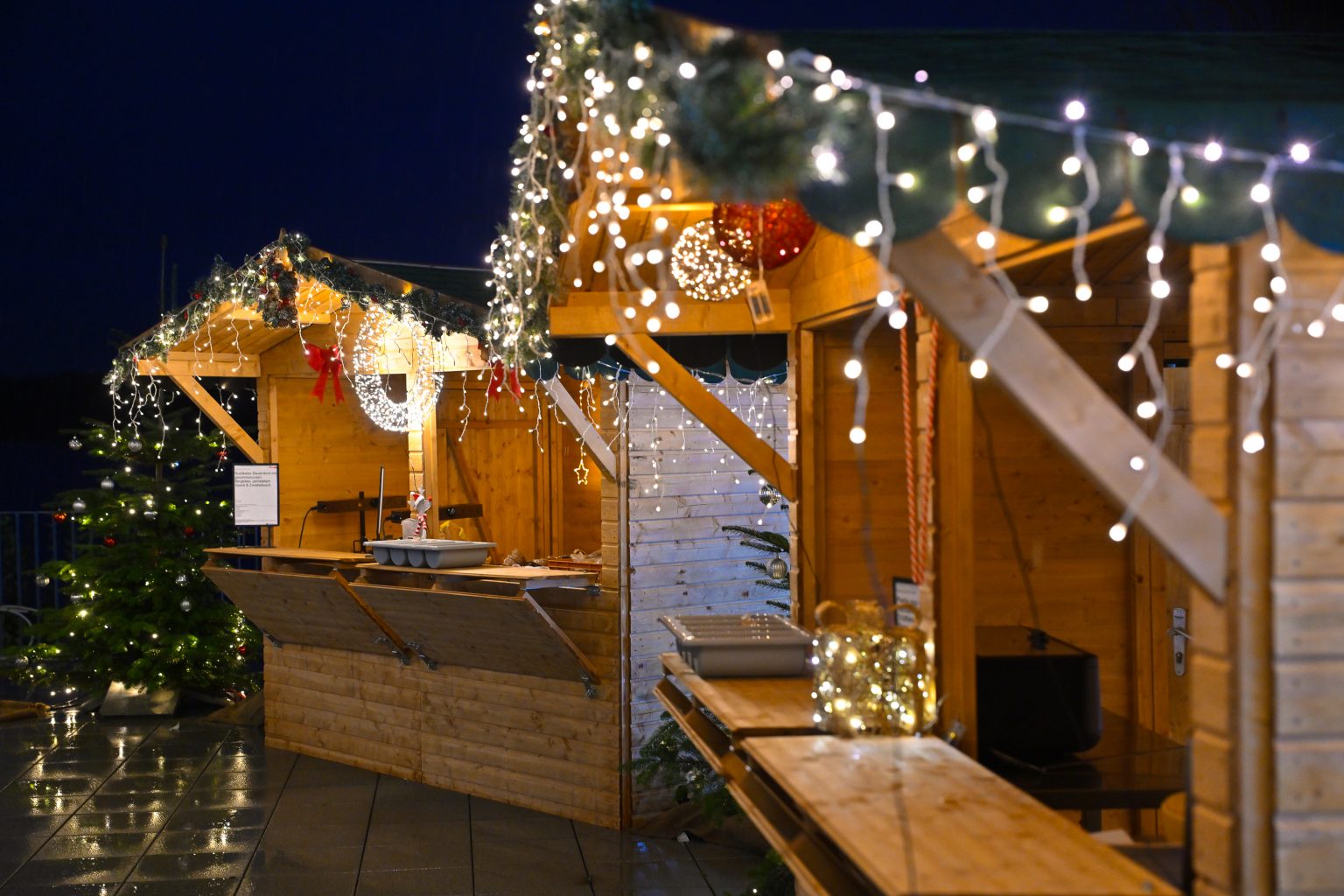 Geschmückte Hütten auf dem Weihnachtsmarkt, gemütliches Licht, Lichterketten und weihanchtliche Dekoration