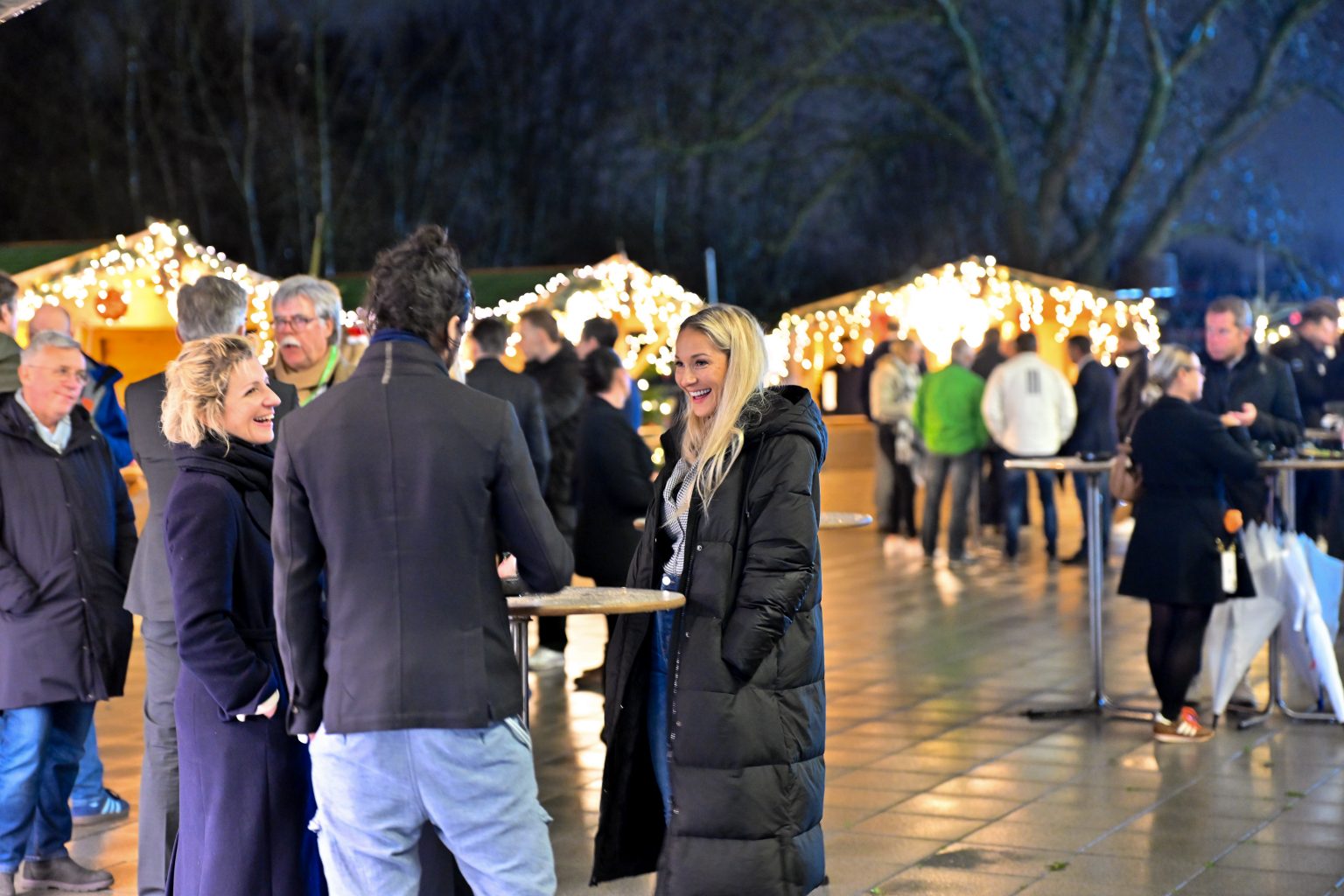 Gäste stehen zusammen und unterhalten sich auf dem Weihnachtsmarkt