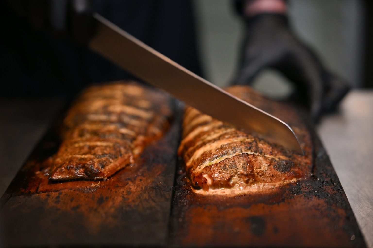 Nahaufnahme eines Flammlachs, der mit einem Messer geschnitten wird.