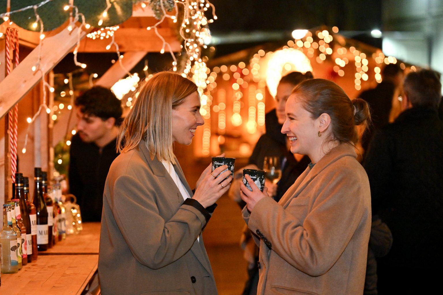 Zwei Frauen unterhalten sich mit Glühwein in der Hand auf dem Weihnachtsmarkt