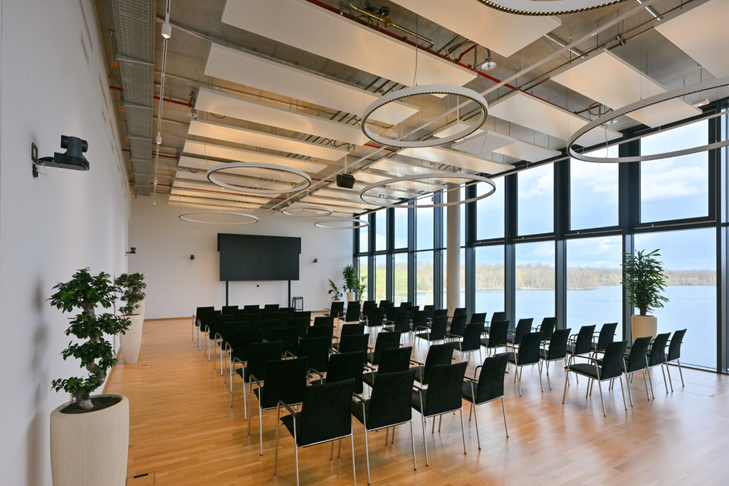 Meetingraum Eventlocation EUREF-Campus Düsseldorf mit Reihen-Bestuhlung und Fensterfront mit Seeblick