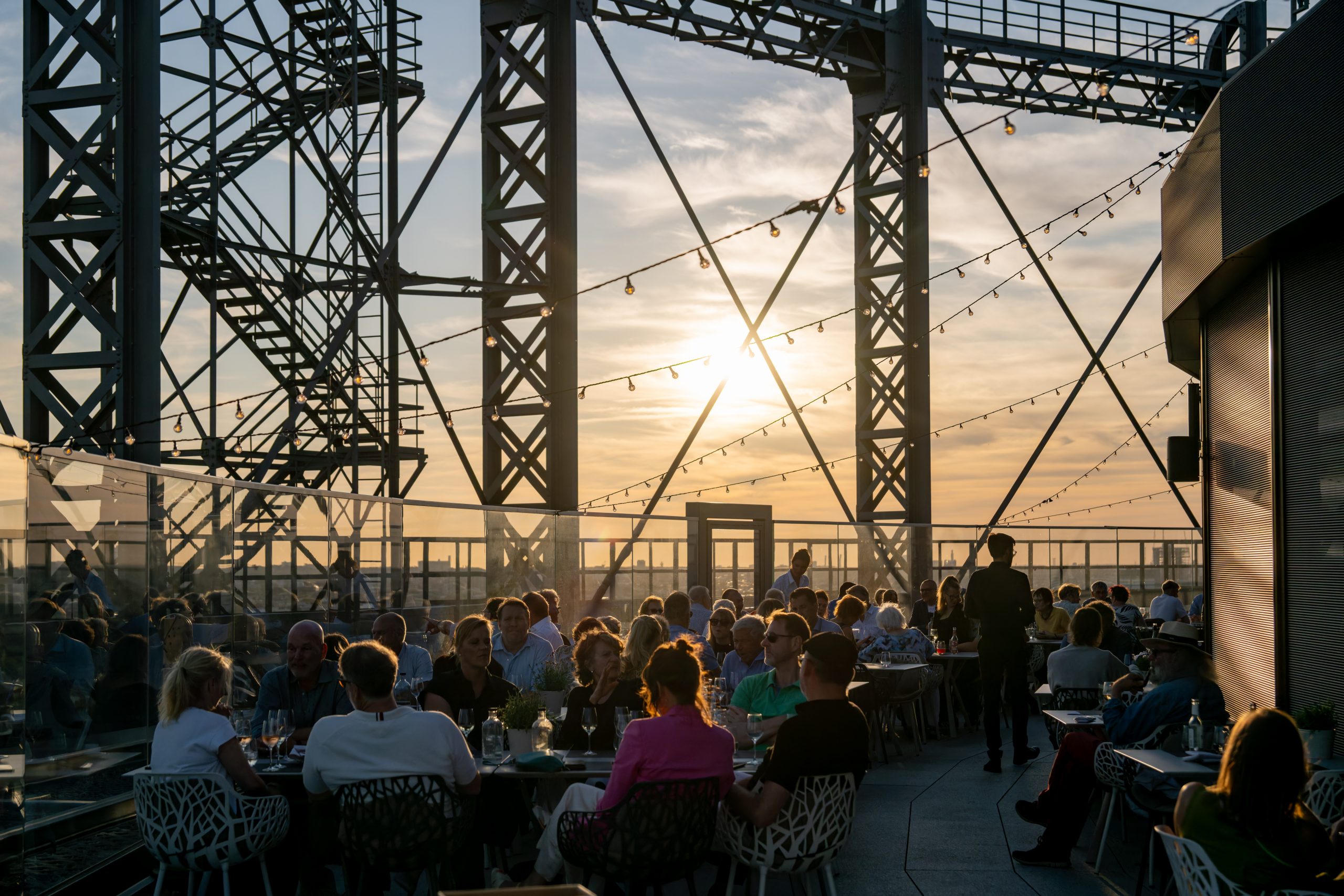 Abendveranstaltung im Sommer auf dem Gasometer SKY - bei Sonnenuntergang sitzen Gäste gemütlich beisammen