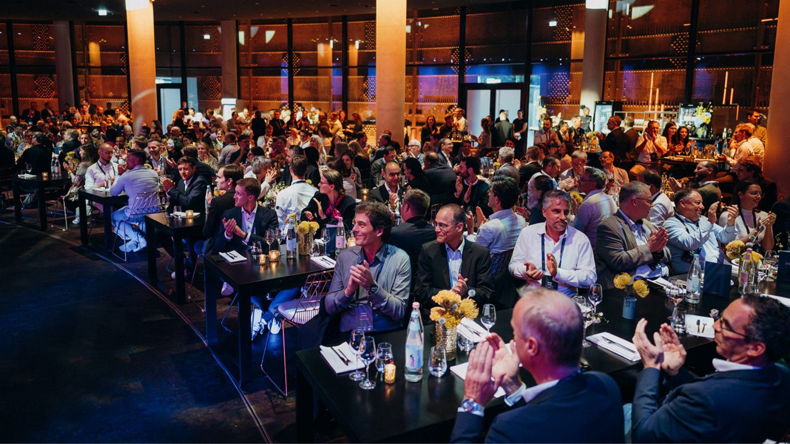Die Gäste der MOMENTUM bei der Abendveranstaltung im Gasometer Forum, beim Dinner mit elegant gedeckten Tischen und Dekoration in blau und gelb