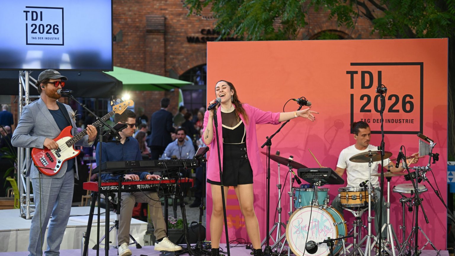 Auf dem EUREF-Plaza performen auf einer Bühne mehrere Musiker mit einer Sängerin in einem pinken Oberteil