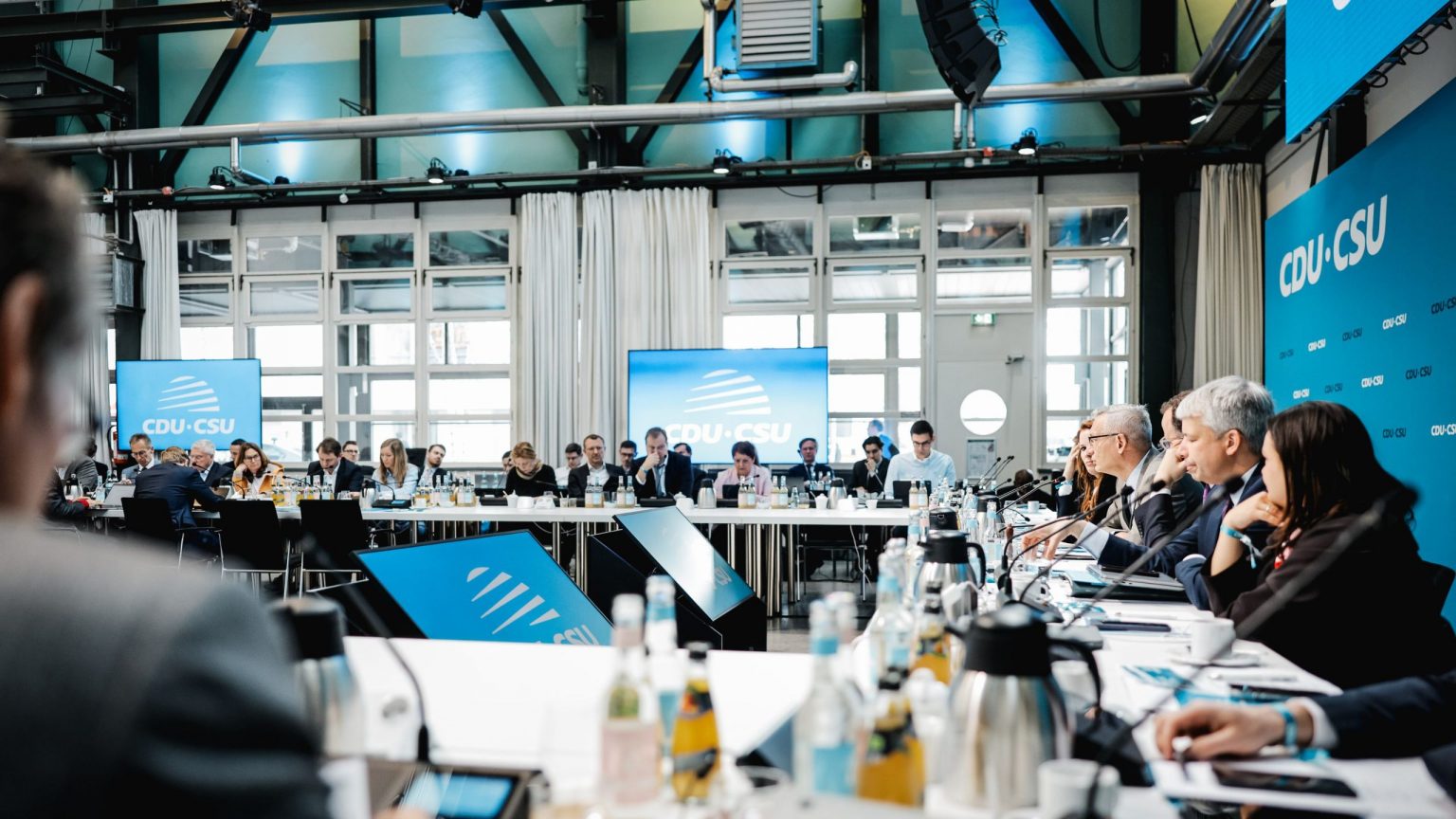 Die Vorstandsklausur in der Werkstatt. Die Teilnehmenden sitzen in einem Viereck an Tischen.