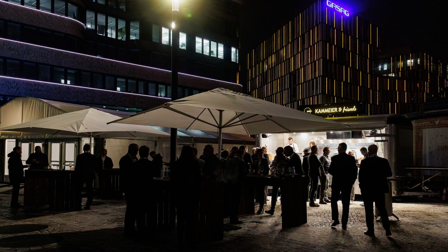 Vor dem Gasometer auf dem EUREF-Plaza kommen Gäste am Foodtruck zusammen.
